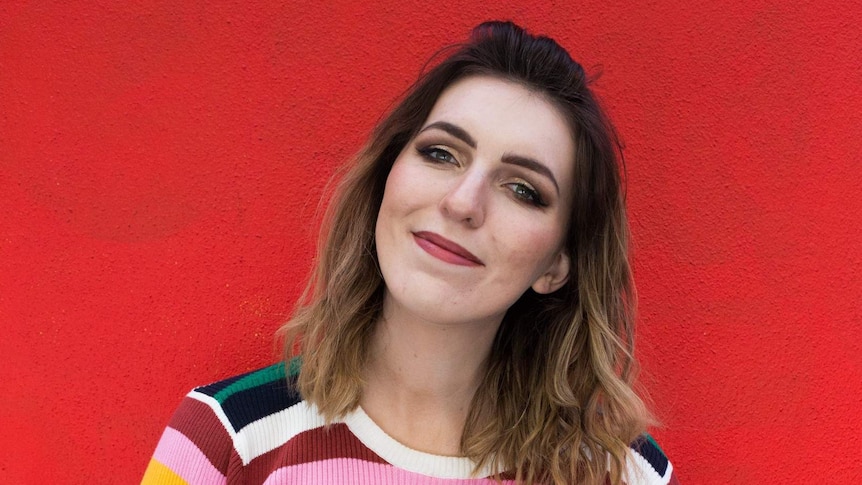 Comedian Melanie Bracewell next to a red background