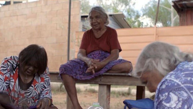 Three elderly Indigenous women make artwork