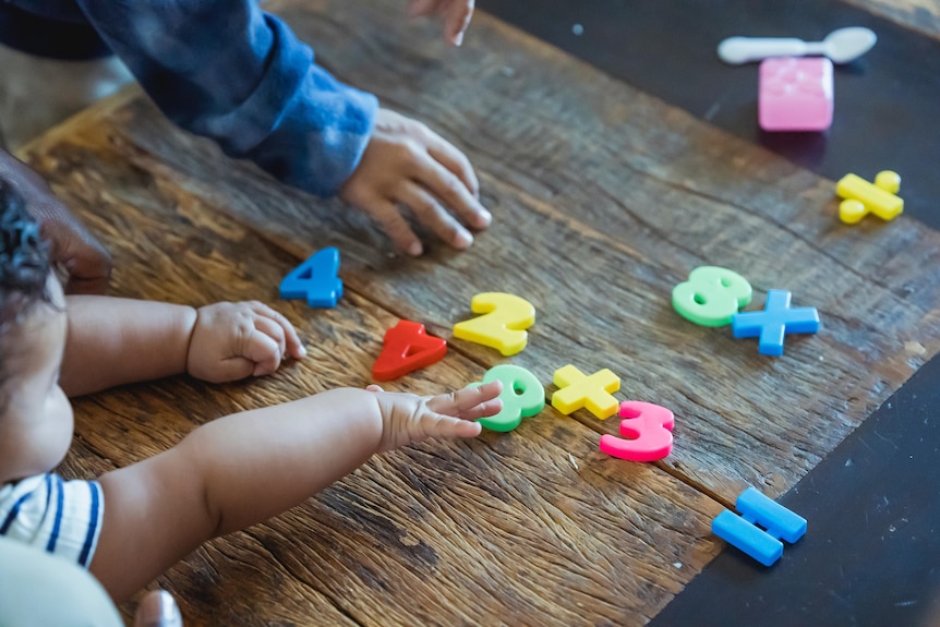 Two cute toddler siblings playing with plastic toys at table