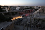 A vehicle drives past damaged buildings in the northern Syrian rebel-controlled town of al-Rai.