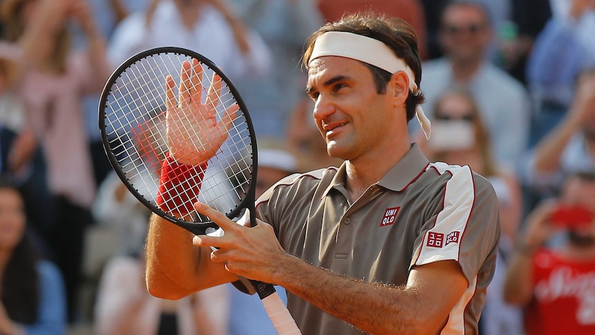 A tennis player claps his racquet in acknowledgement of the crowd after winning his match in Paris.