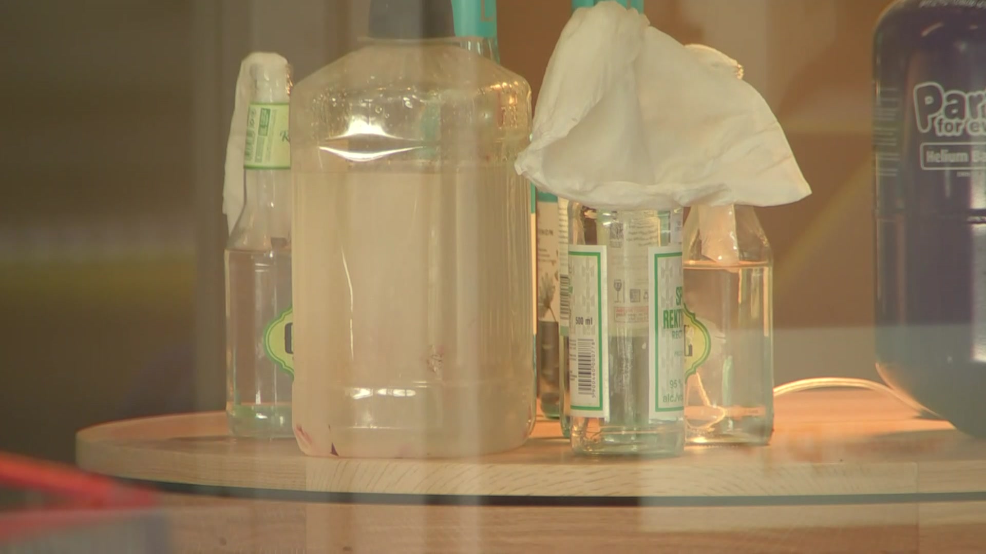Bottles of clear fluid viewed through a glass window