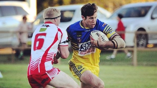 Rugby league player holding the ball runs past a defender.