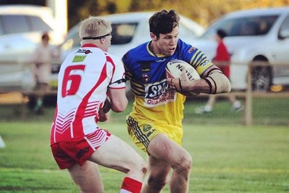 Rugby league player holding the ball runs past a defender.