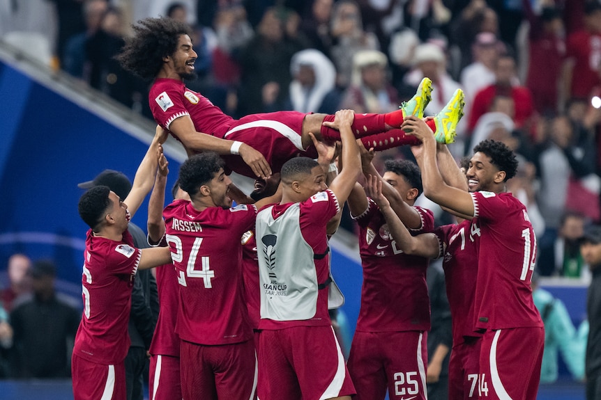 Qatar players throw one of their teammates in the air as they celebrate winning Asian cup final.