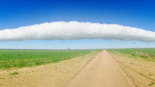 A large roll cloud over a remote road.