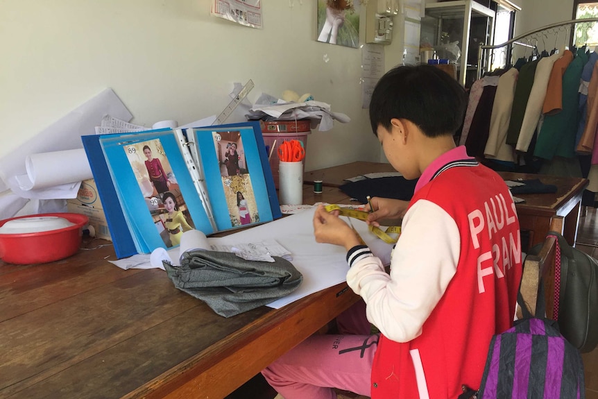 Young girl learning how to sew in Laos