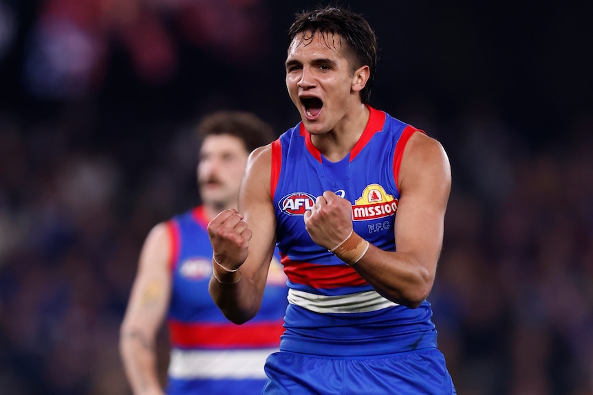 A Western Bulldogs AFL player pumps his fists as he celebrates a goal.
