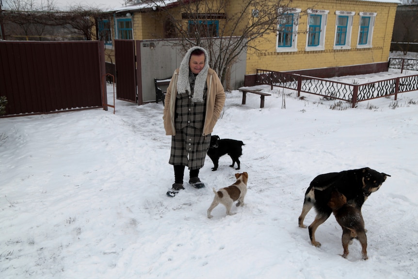 A woman walks with her dogs down a snow-covered street