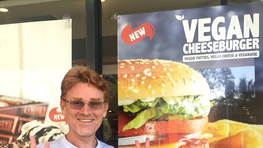 Vegan Greg McFarlane in front of poster