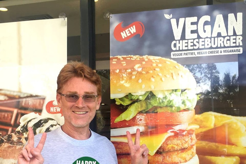 Vegan Greg McFarlane in front of poster