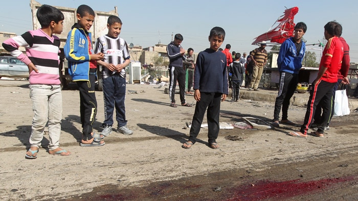 Children look at blood on the ground after a bombing in Sadr City, Baghdad.