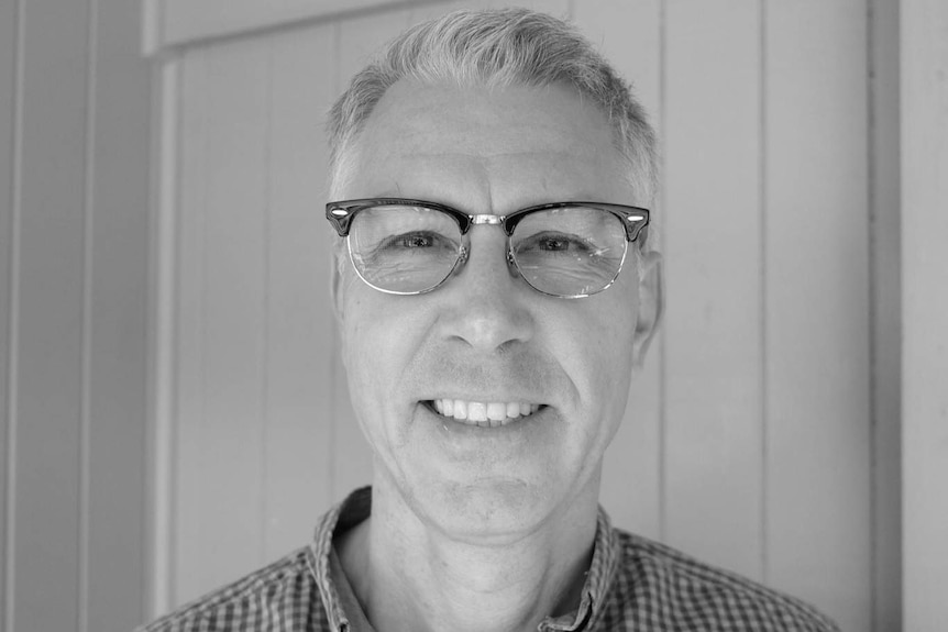 Black and white photo of a man with grey hair, wearing glasses.