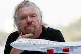 Grey-haired man with goatee with model airplane in foreground