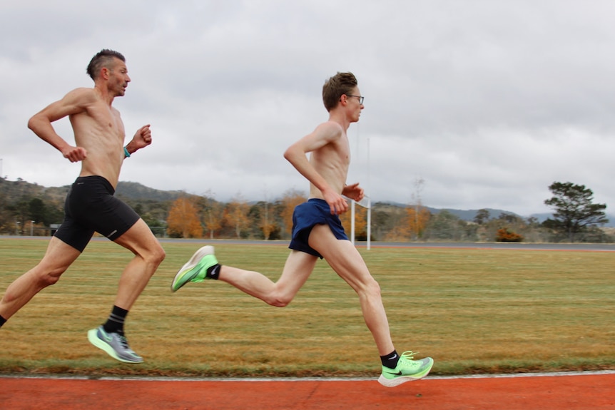 Two men run on a running track.