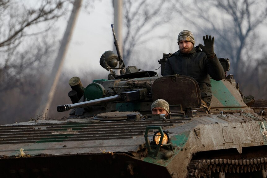 A Ukrainian serviceman waves from a tank in Ukraine.