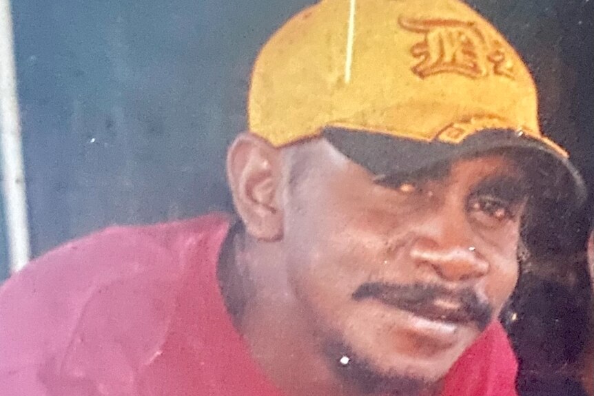 a young aboriginal man wearing a red shirt and yellow cap