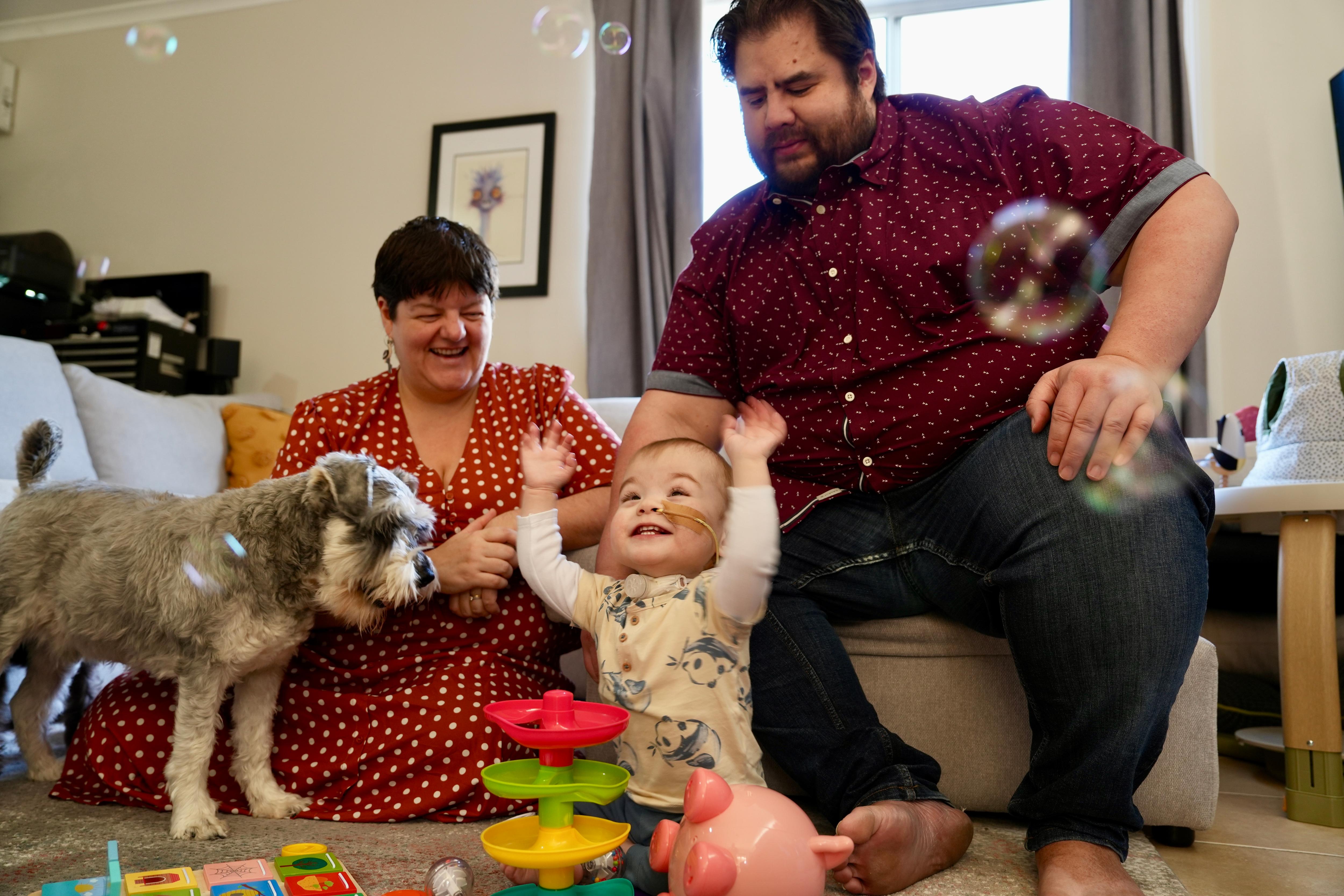 A smiley Atticus, now 18 months old, with his parents Sim and Warwick Nation.