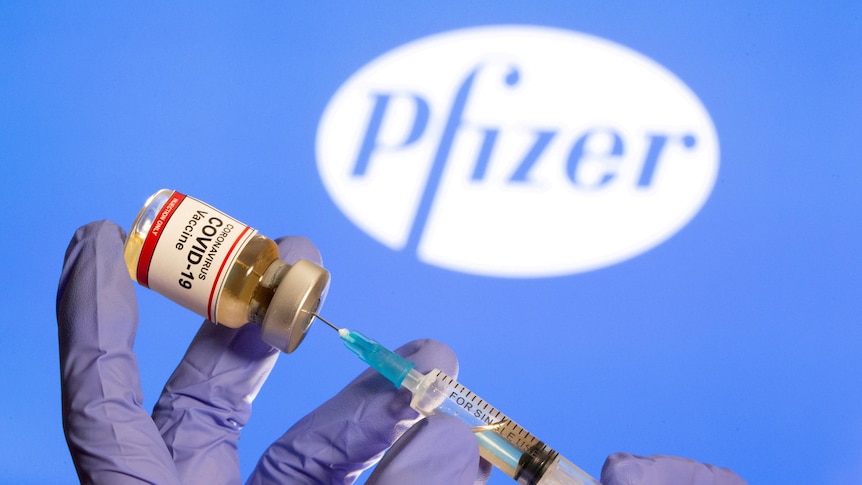 A woman holds a small bottle labeled with a 'Coronavirus COVID-19 Vaccine' sticker.