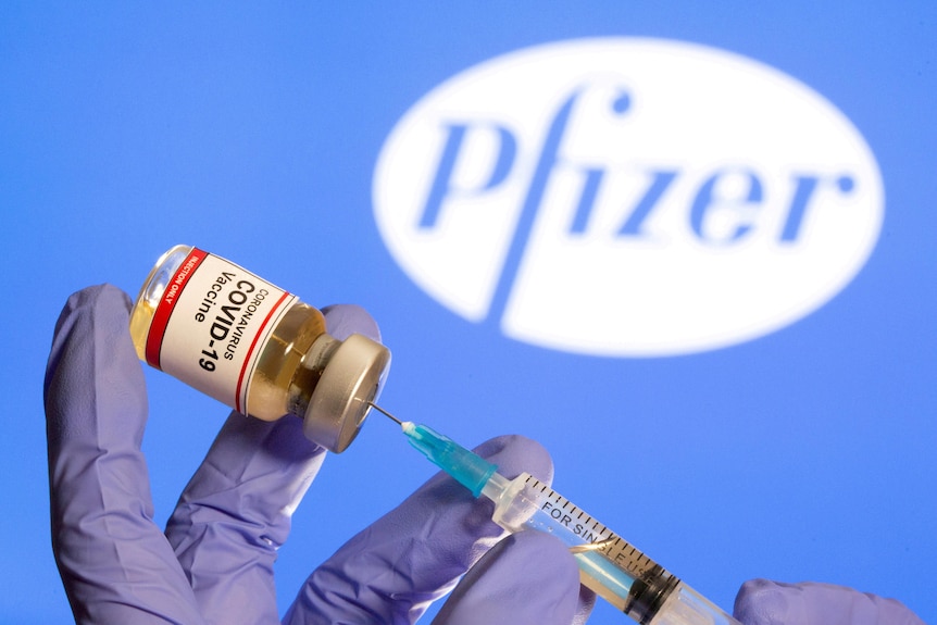 A woman holds a small bottle labeled with a 'Coronavirus COVID-19 Vaccine' sticker.