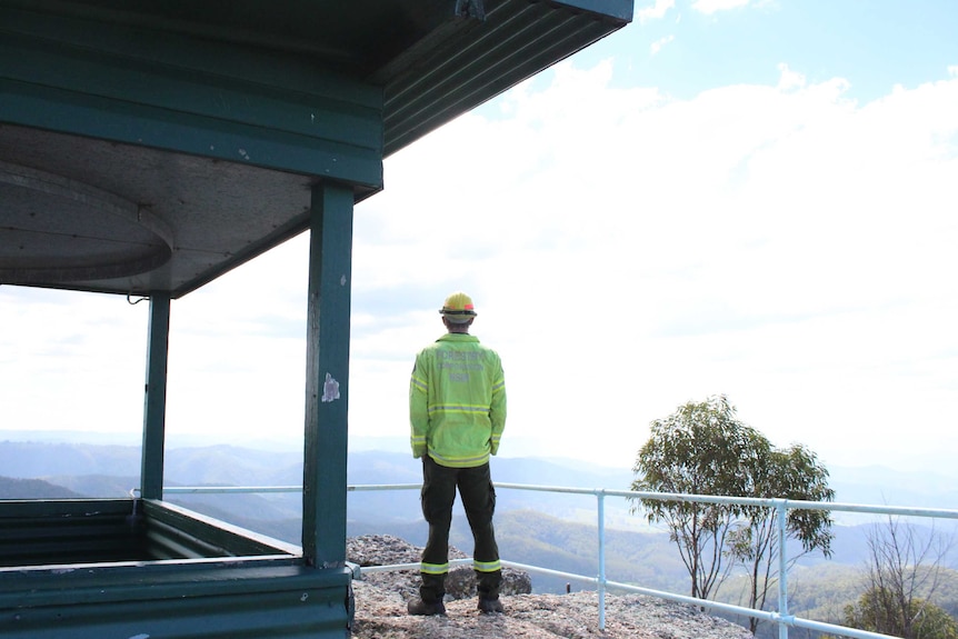 A man standingon a cliff looking at the view.