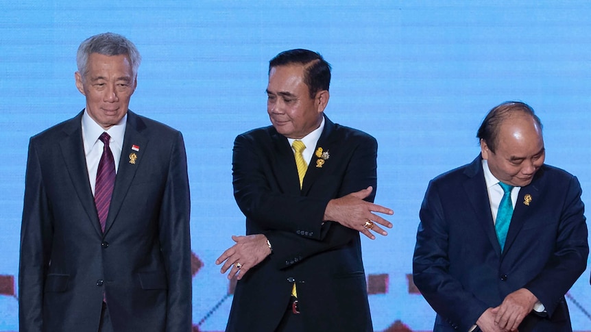 Thailand's Prime Minister Prayuth Chan-ocha (centre) reaches out to grab hand of Lee Hsien Loong.