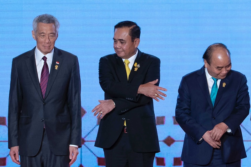 Thailand's Prime Minister Prayuth Chan-ocha (centre) reaches out to grab hand of Lee Hsien Loong.