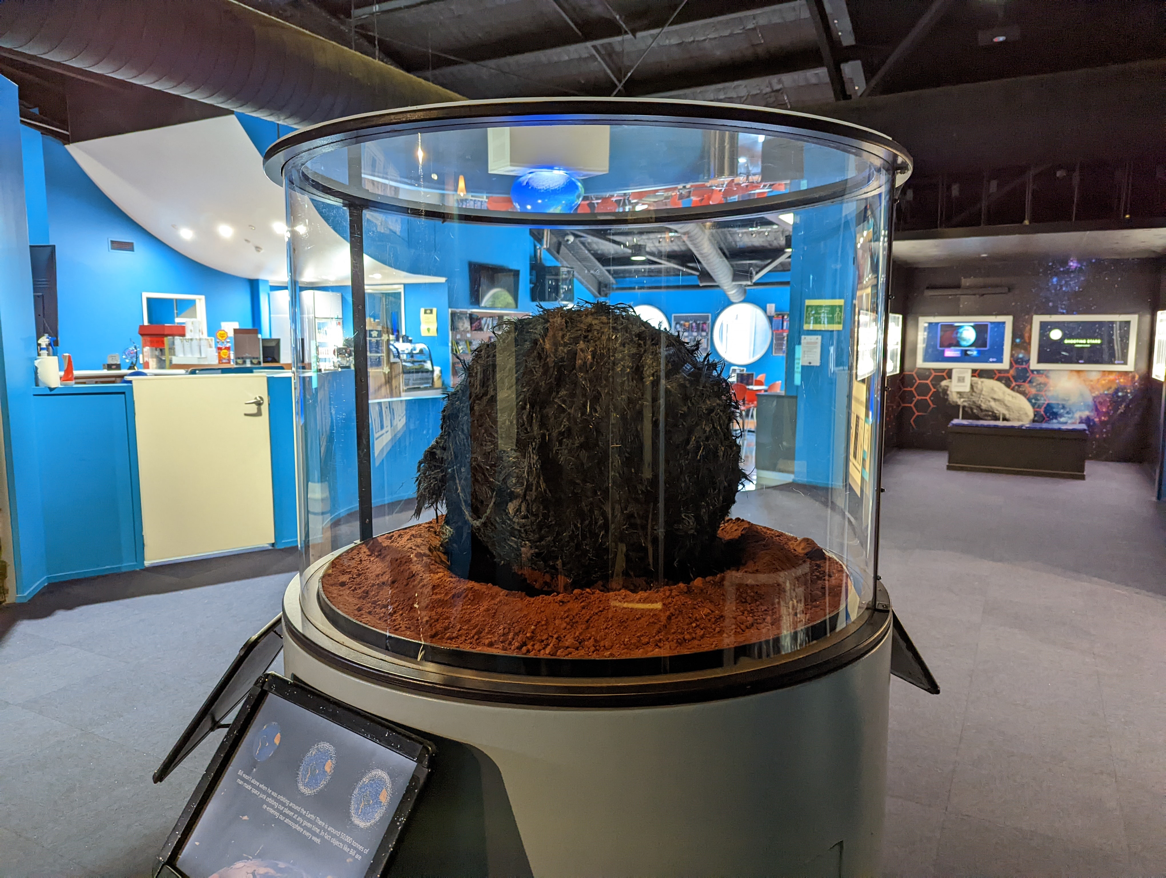 A large ball of space junk on display in a glass container