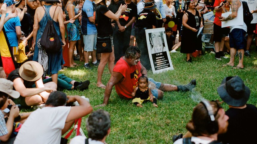 A man sits in the middle of a circle with a child at Yabun Festival, 2019.