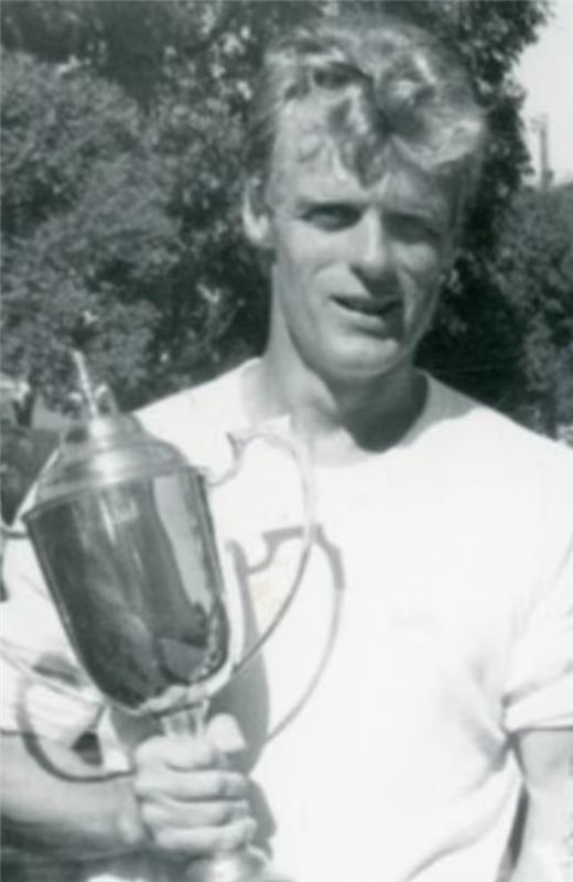 Black and white image of a man holding a sports trophy 