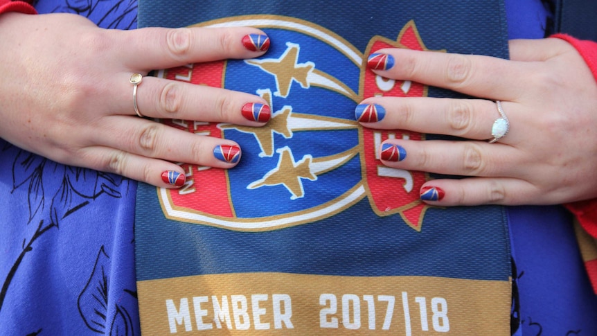 A woman's fingernails are painted with the Jets colours, over
