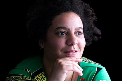 A woman in a green shirt looking inspired with a black background