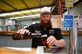 A photo of Matty Wilson pouring a beer in his new brewery