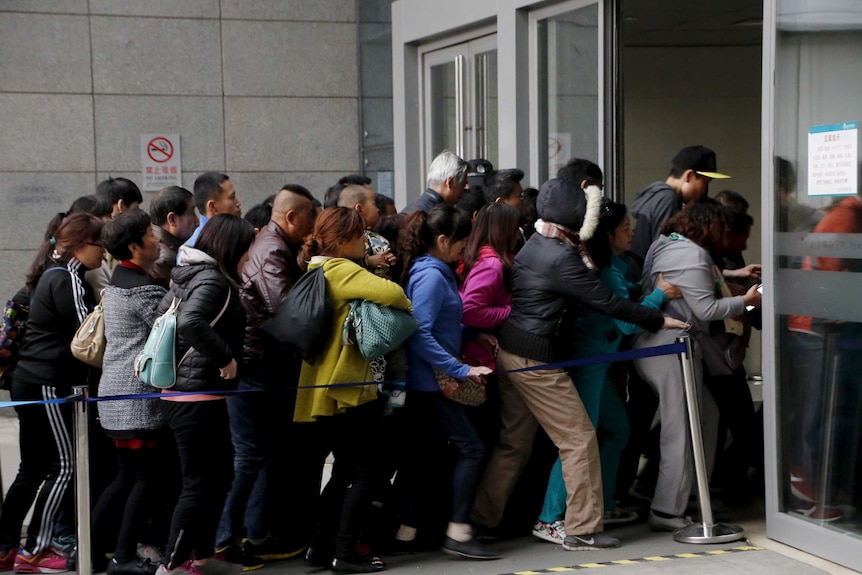 A crowd of people rush into a hospital in China.