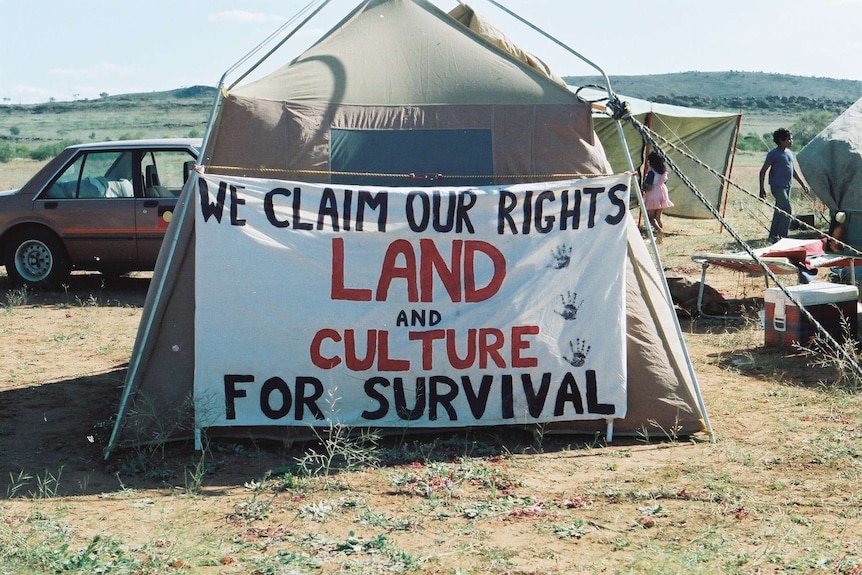 A tent and sign reading 'we claim our rights, land and culture for survival'.