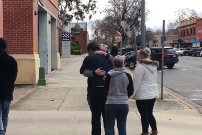 A man hugging friends outside court