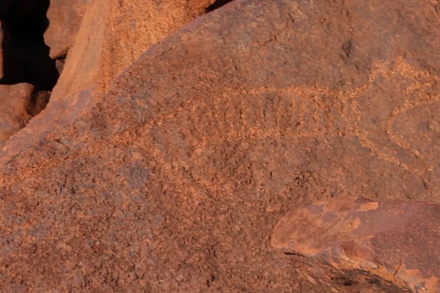 Indigenous rock art of a tiger on red rock.