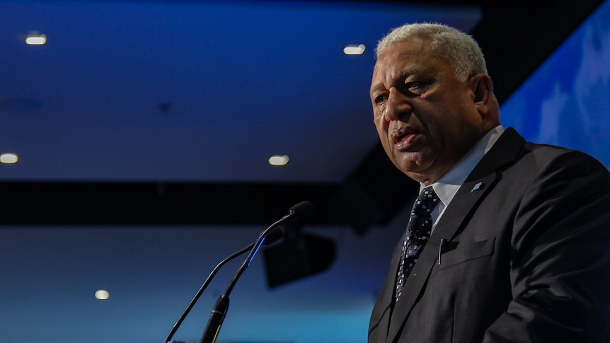 Fiji's Prime Minister Frank Bainimarama makes a speech at a podium at a climate change conference at the MCG.