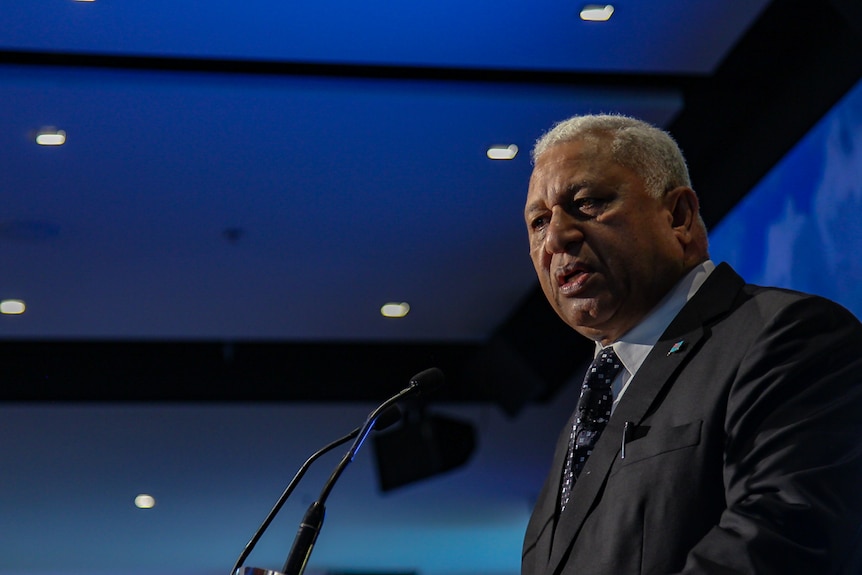 Fiji's Prime Minister Frank Bainimarama makes a speech at a podium at a climate change conference at the MCG.