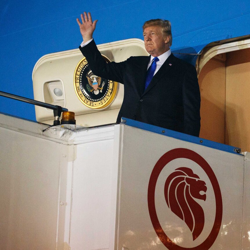 Donald Trump stands at the door of the presidential plane, Air Force One, and waves.