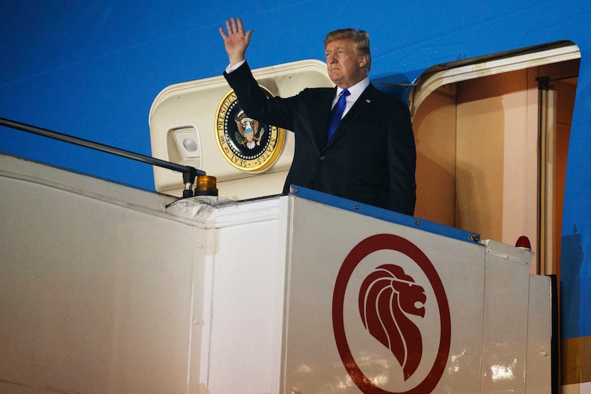 Donald Trump stands at the door of the presidential plane, Air Force One, and waves.