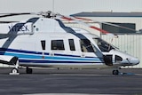 A helicopter, stationary, on the tarmac at an airport