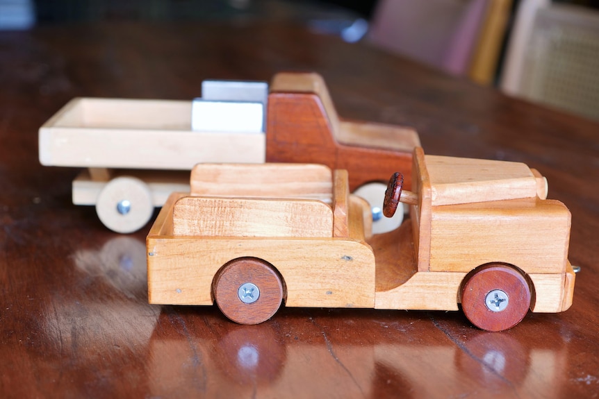 Close up of two hand made timber toy trucks on a table. 