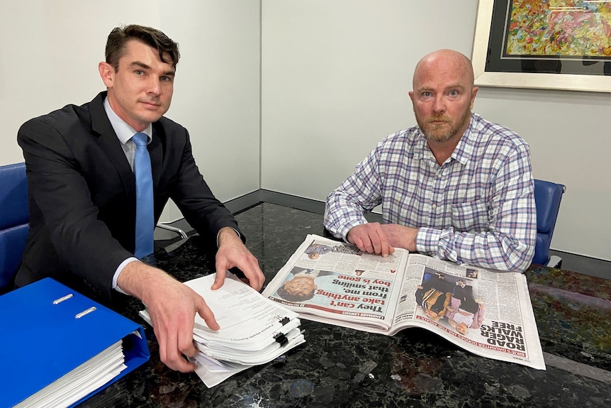 Lawyer James Lavercombe and client David Welsh sit at a table in an office.