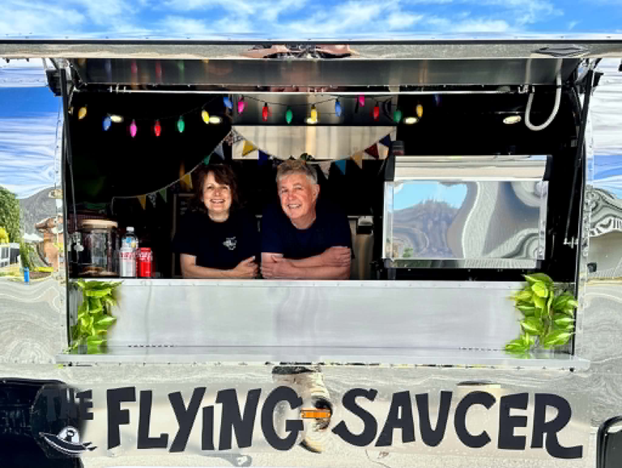A couple stands inside a food delivery truck.