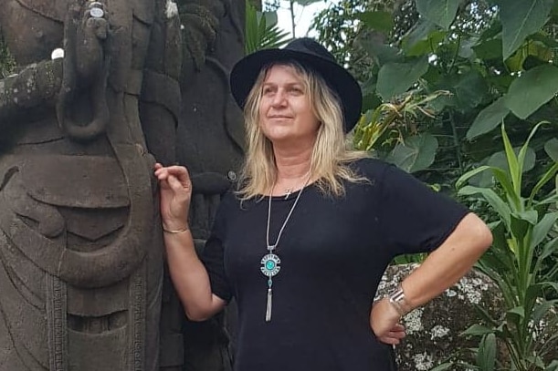 A woman leans against a statue.