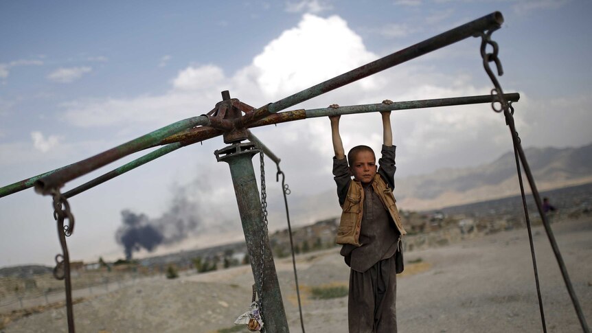 An Afghan boy hangs from a merry-go-round on a hill top in Kabul, Afghanistan