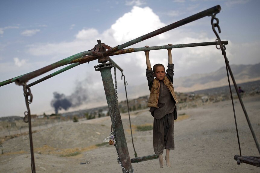 An Afghan boy hangs from a merry-go-round on a hill top in Kabul, Afghanistan