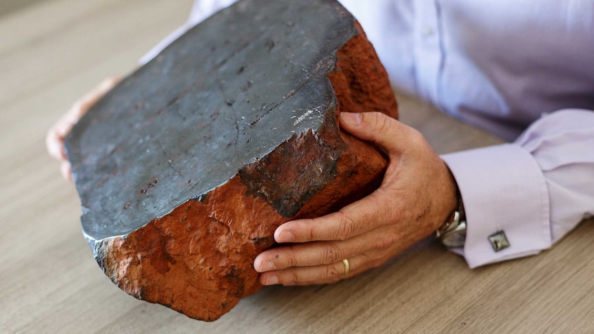 Hands of Vince Agar, Australian Vanadium, holding a large piece of vanadium ore