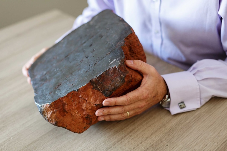 Hands of Vince Agar, Australian Vanadium, holding a large piece of vanadium ore